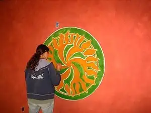 Students at Cal Poly Humboldt use egg paint to create this logo for the interior wall of the Campus Center for Appropriate Technology.