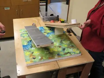 The Inclined Planes experiment is designed to slide objects down an angular plane with different friction force cutouts such as a metal slate, carpet ruminant, and a rectangle of wood.