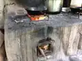 Wood is inserted into the chambers on the side of the stove. The flames rise through a chimney, and the heat escapes through the top opening, where it can be used to cook food.