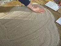 Fig.8 spreading a fine layer of sand on top of the Thermal mass sub-floor before laying the fire bricks